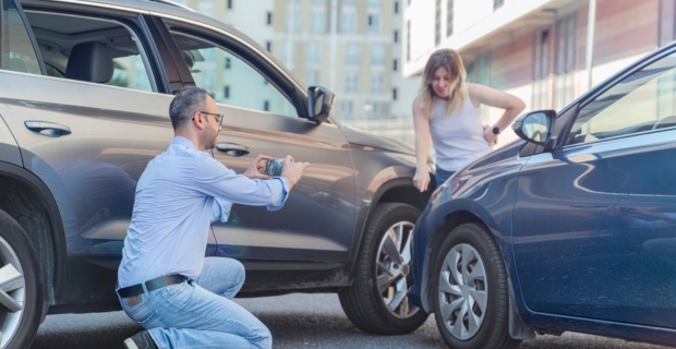 Un homme prend des photos d’un accident de voiture pendant qu’une femme montre les dommages.