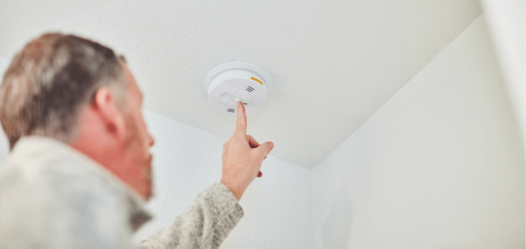 Un propriétaire vérifie un avertisseur de fumée lors d’une inspection de sécurité-incendie à domicile.