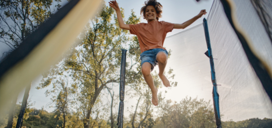 Jeune personne sautant et profitant de son trampoline en été. 