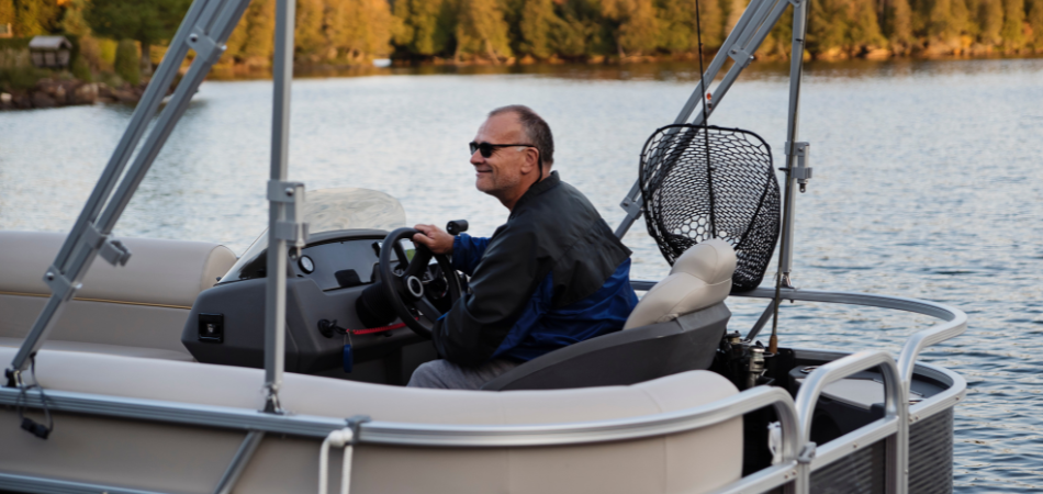Une personne conduit un bateau avec, en arrière-plan, une rangée d’arbres aux couleurs d’automne.