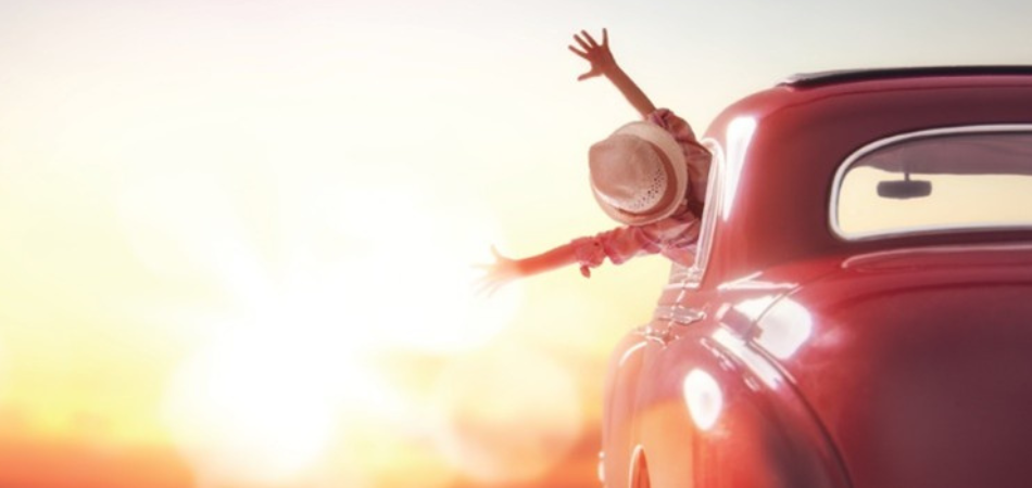 Une jeune femme est heureuse et fière au volant de sa Coccinelle