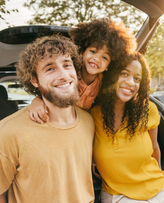 Une famille pose sous le hayon ouvert de sa voiture avant de partir en voyage.