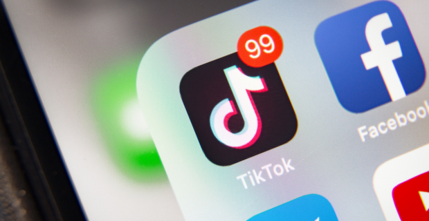 Un gros plan de l’icône de l’appli TikTok avec 99 notifications, sur l’écran d’un téléphone intelligent. 