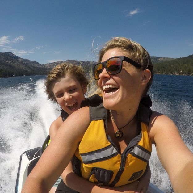 Un parent et son enfant, portant des gilets de sauvetage, rient et sourient alors qu'ils roulent sur leur Sea-Doo.