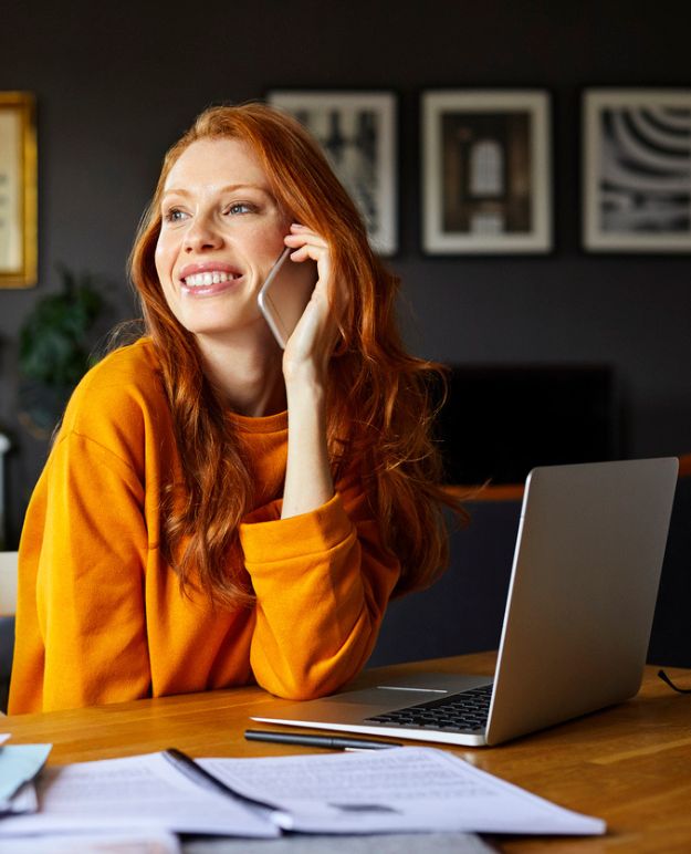 Une femme au téléphone avec son ordinateur portable ouvert devant elle.