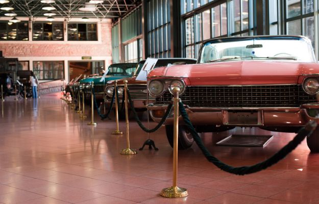 Des voitures classiques sont exposées derrière des cordes de velours dans un musée automobile.