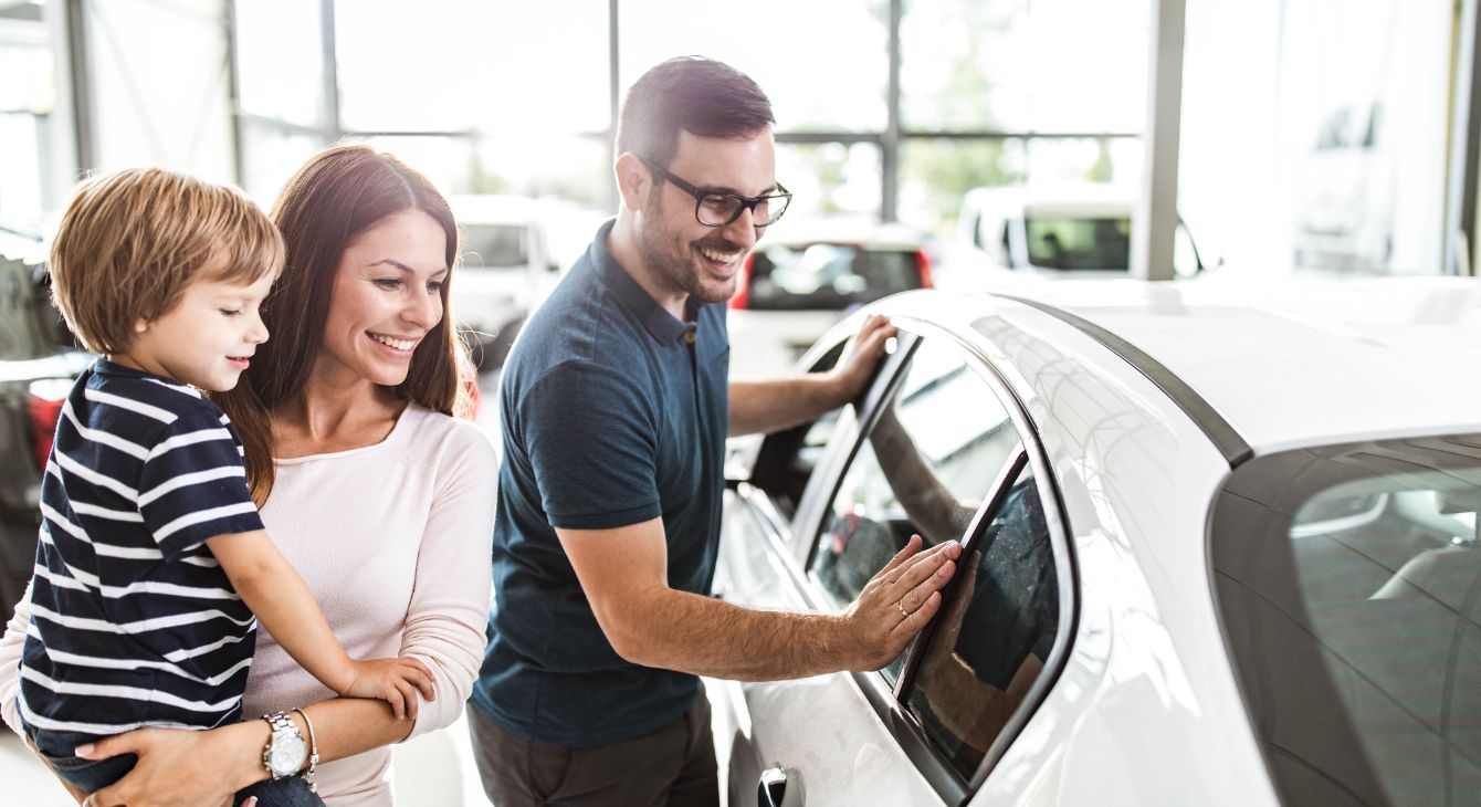 A family looking at new cars inside a car dealership.