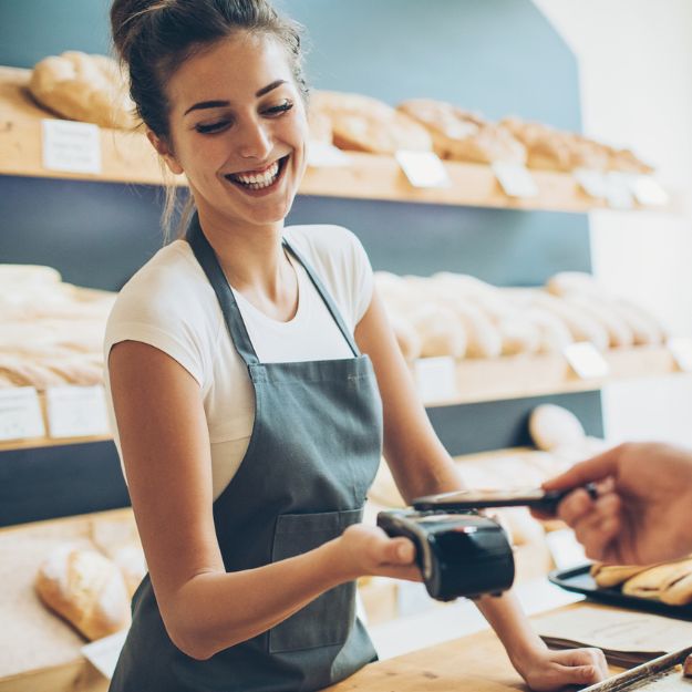 Une femme qui tient le comptoir de sa boulangerie.