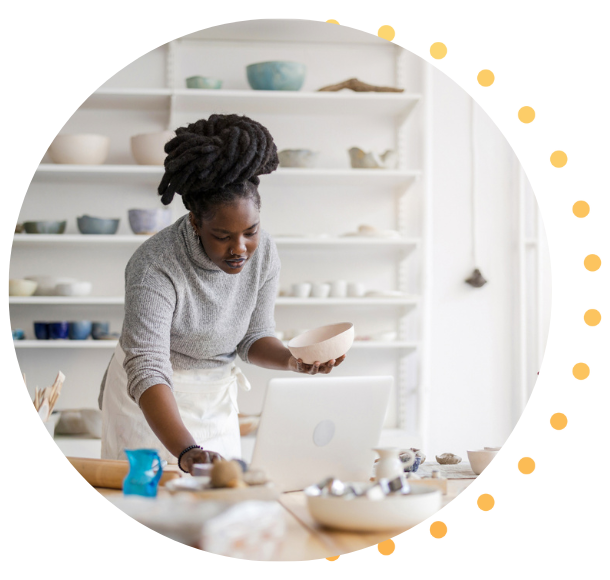 Une femme noire avec des tresses fabrique de la poterie pour son magasin.