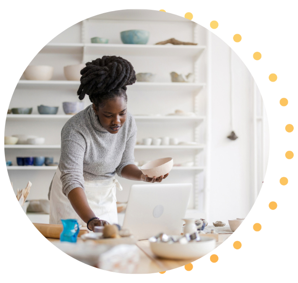 A Black woman with braids is making pottery for her store.