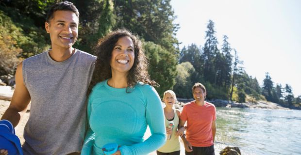 Deux couples marchent bras dessus bras dessous le long du bord d'une belle rivière par une journée ensoleillée en Alberta.