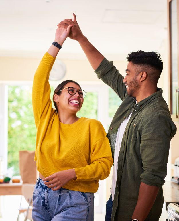 A young couple dancing together in their new home.