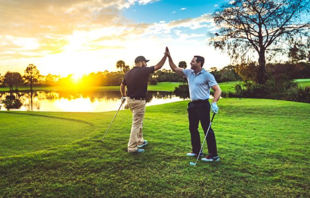 Deux golfeurs font un high-five sur le green.