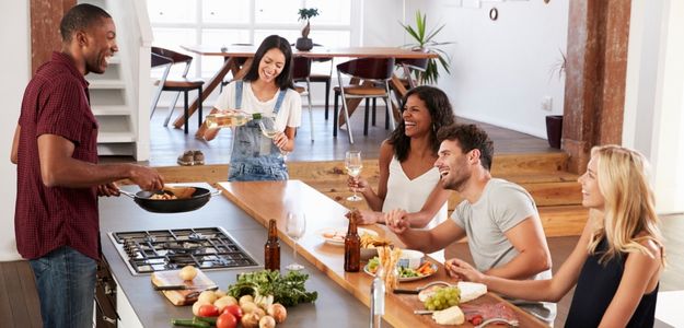 Un groupe de cinq amis réunis autour d'un îlot de cuisine profitant d'une conversation animée