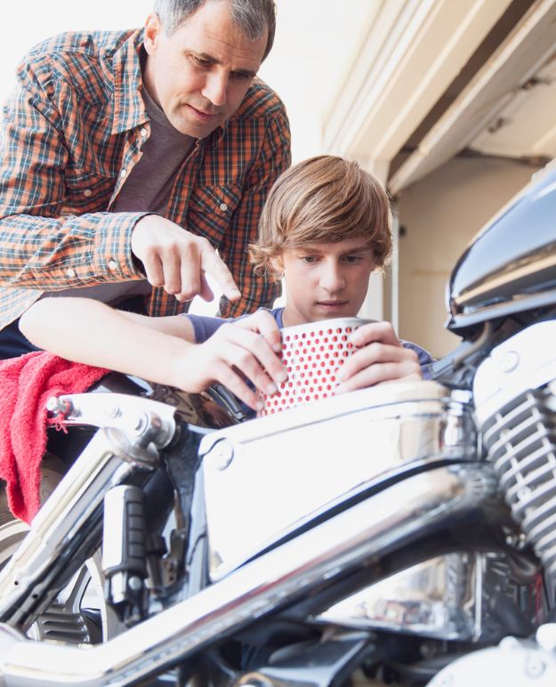 Un homme dans la cinquantaine, apprenant à son fils comment entretenir un vélo.