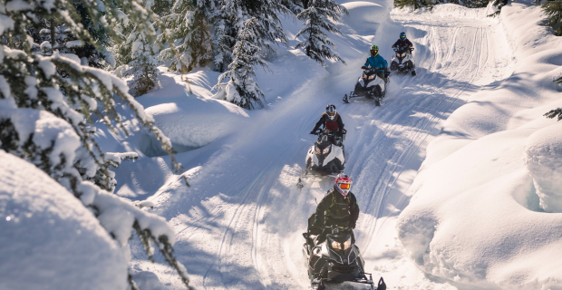 Un groupe de personnes faisant de la motoneige sur une piste en hiver.