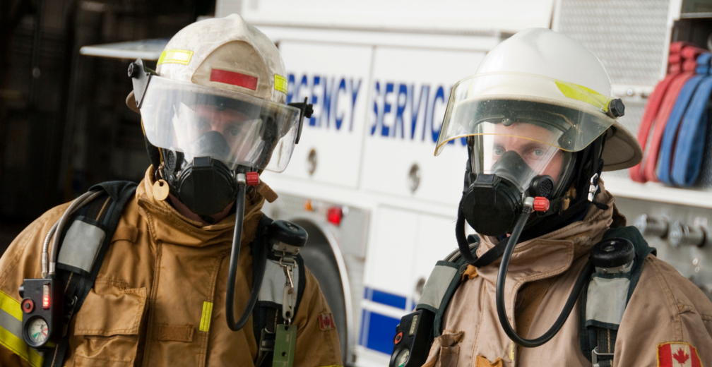 Deux pompiers canadiens en tenue d’intervention devant leur camion de pompiers discutent d’Intelli-feu et donnent leurs meilleurs conseils pour prévenir les incendies.