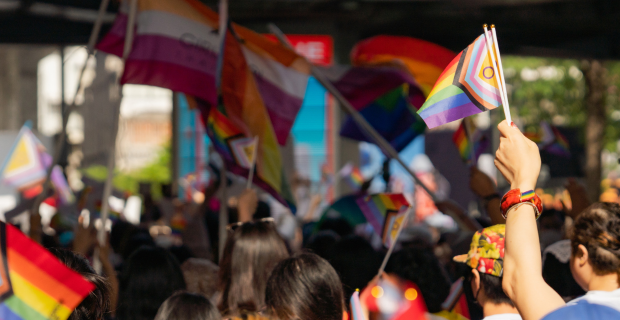 Des personnes brandissant différents drapeaux de la Fierté à l’extérieur