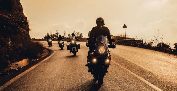 Une photo sépia de quatre motocyclistes qui se suivent de manière sécuritaire, un après l’autre, dans une courbe.