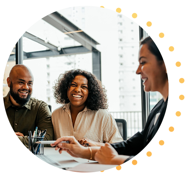 Un homme et une femme souriants sont assis à un bureau dans un environnement professionnel. Une femme lisant sur son téléphone.