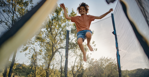 Jeune personne sautant et profitant de son trampoline en été. 