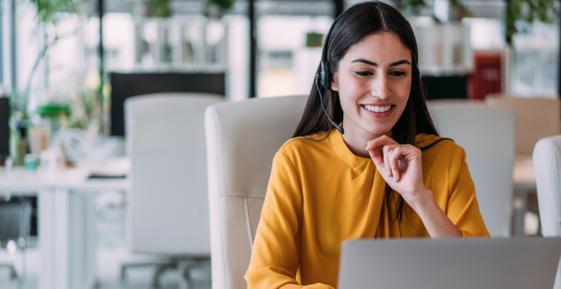 Courtière en assurance discutant d’une couverture avec un client par téléphone, équipée d’un casque d’écoute et d’un ordinateur portable dans un bureau.   