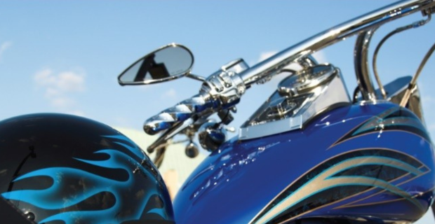 Gros plan d'une moto bleue avec des pièces chromées et des autocollants de flammes sur le réservoir et le casque.