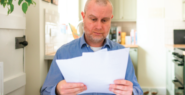 Personne en chemise bleue lisant des journaux dans une cuisine.